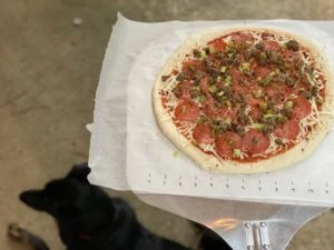 Pizza on parchment paper on a pizza peel