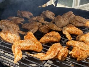 Chicken wings smoking on the grill grate