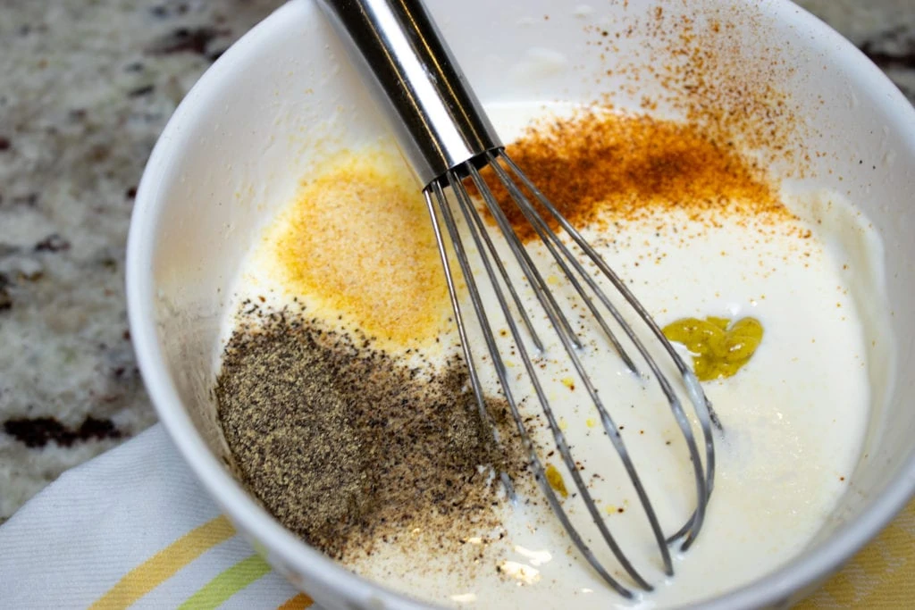 White BBQ sauce in a bowl with a whisk