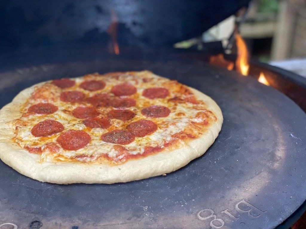 Pepperoni pizza cooking on a pizza stone in the Big Green Egg