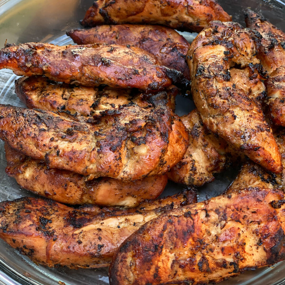 Smoked chicken tenders together resting on a glass pie plate.