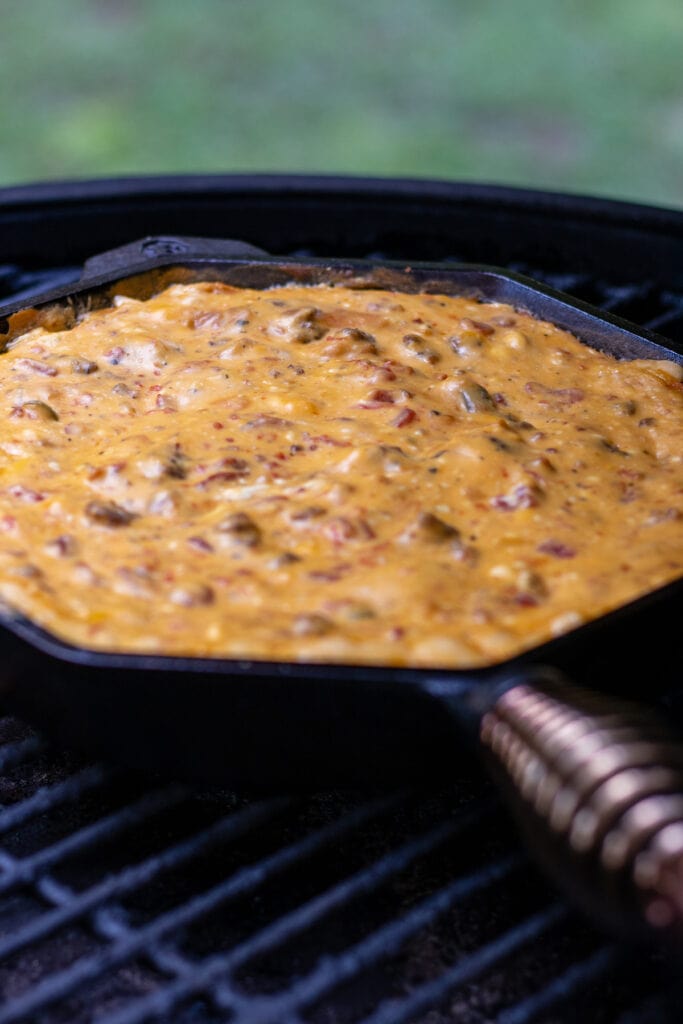 Blended smoked cheese dip in a cast-iron skillet on a grill