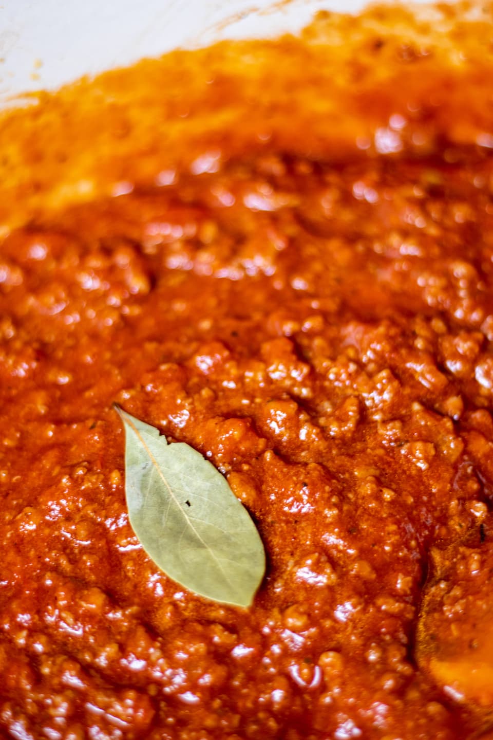 a bay leaf on top of bright red spaghetti sauce