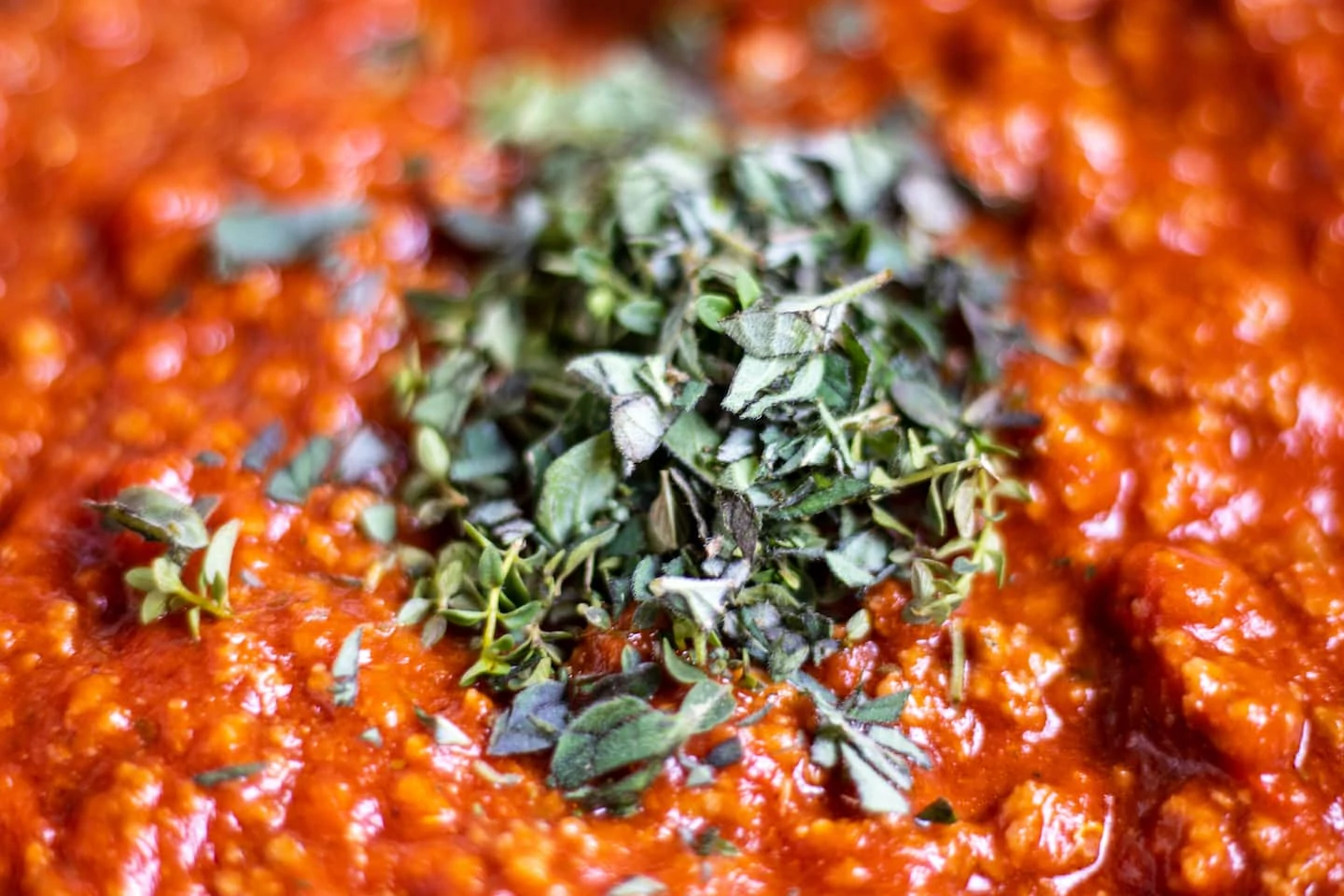 Chopped green herbs on a bright red spaghetti sauce