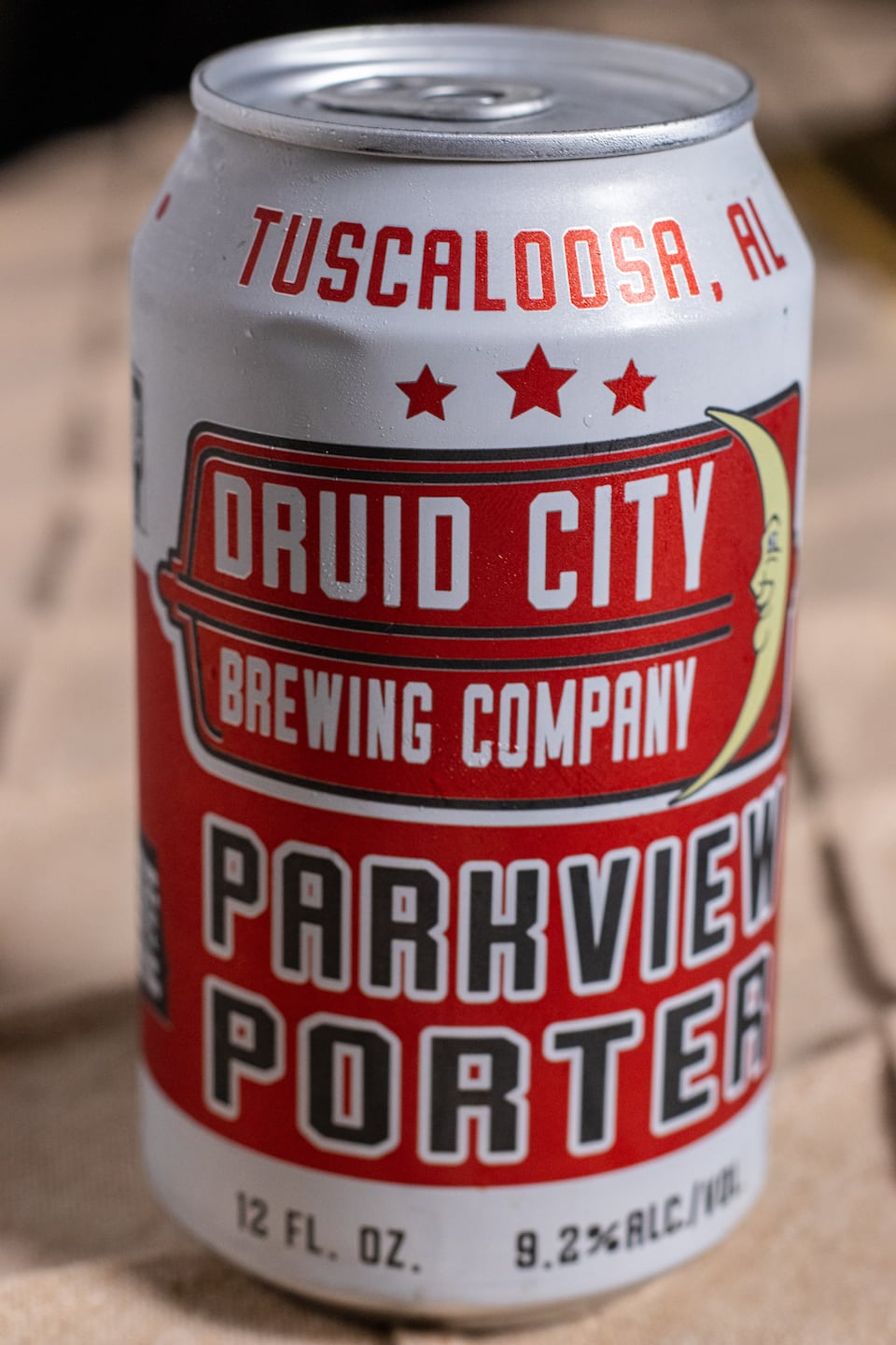 Beer can with Tuscaloosa, AL at top in red on a white background, three red stars before it transitions to white text on a red background that says "Druid City Brewing Company" with a yellow crescent moon with a smiling face on it. Then black text outlines in white that says "Parkview Porter" Bottom of the can says 12 ounce and 9.2% ABV. 