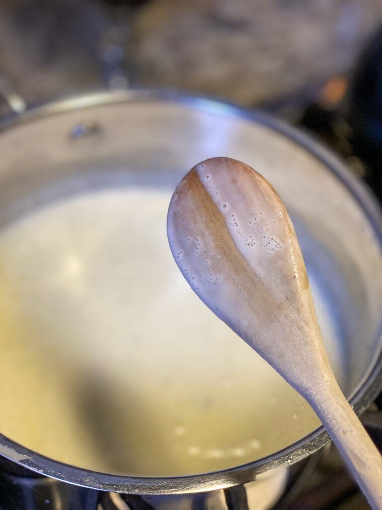 a wooden spoon with a line swiped by a finger through the run of custard from the pot below it. 