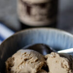 close up of tan porter ice cream in a bowl with a blurred bottle of porter in the back ground.