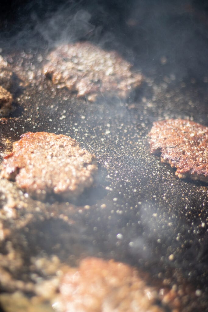 burgers cooking on a griddle