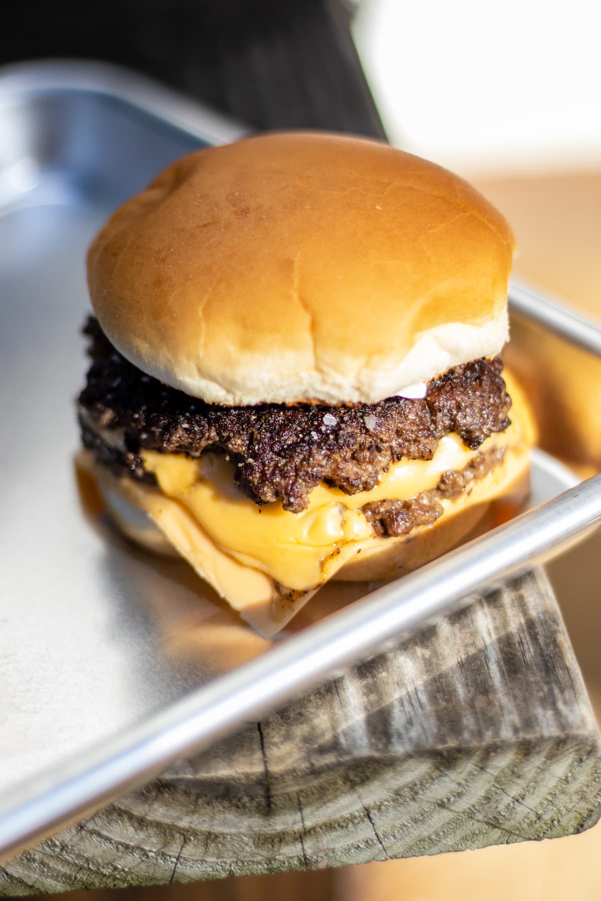 a double hamburger with melted American cheese on a bun and sitting on a baking sheet