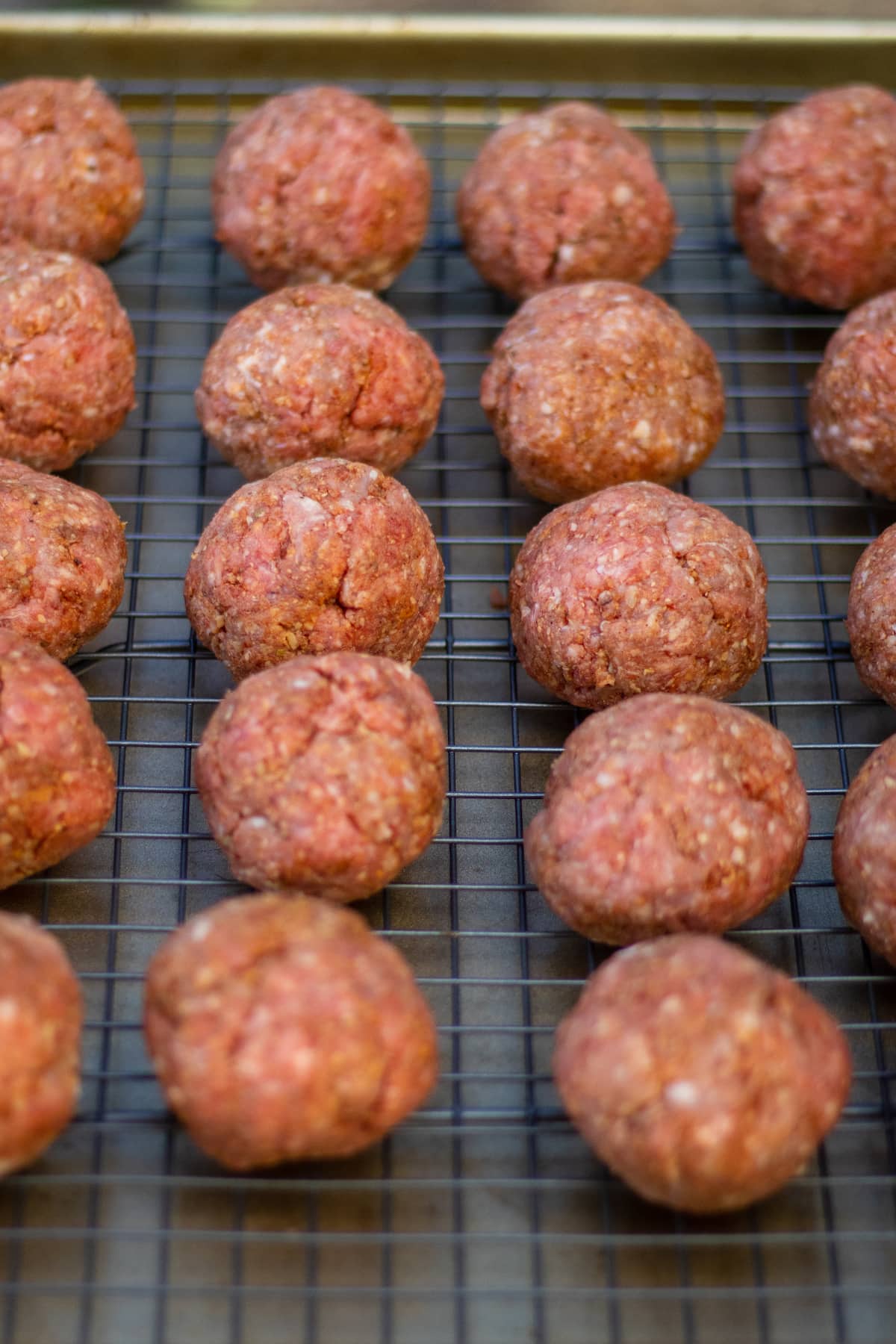 raw meatballs resting on a wire rack