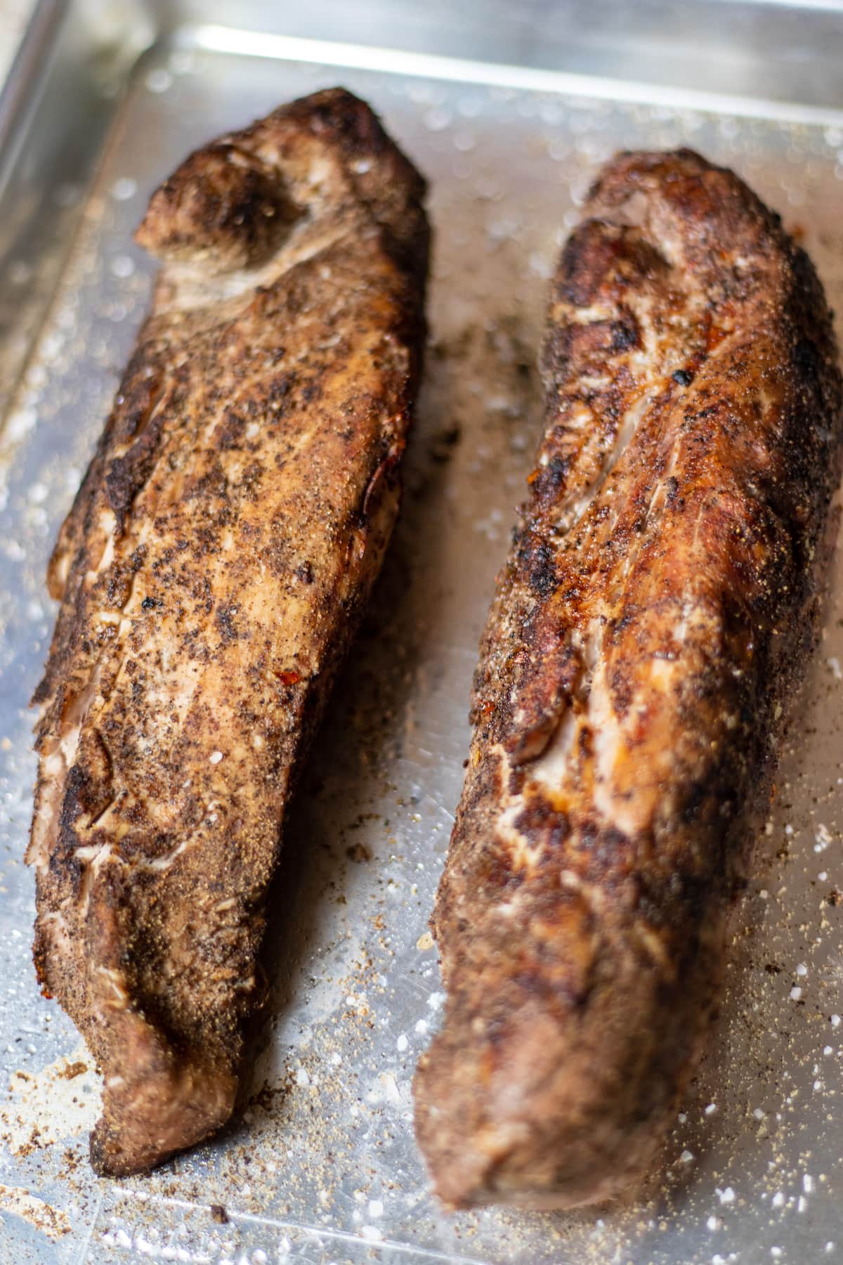 seared pork tenderloins on an aluminum cookie sheet.