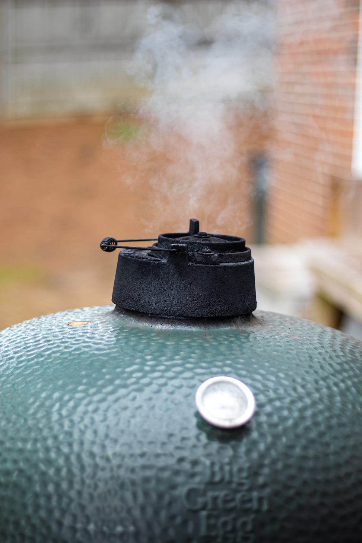 Big Green Egg with smoke coming out of the top.