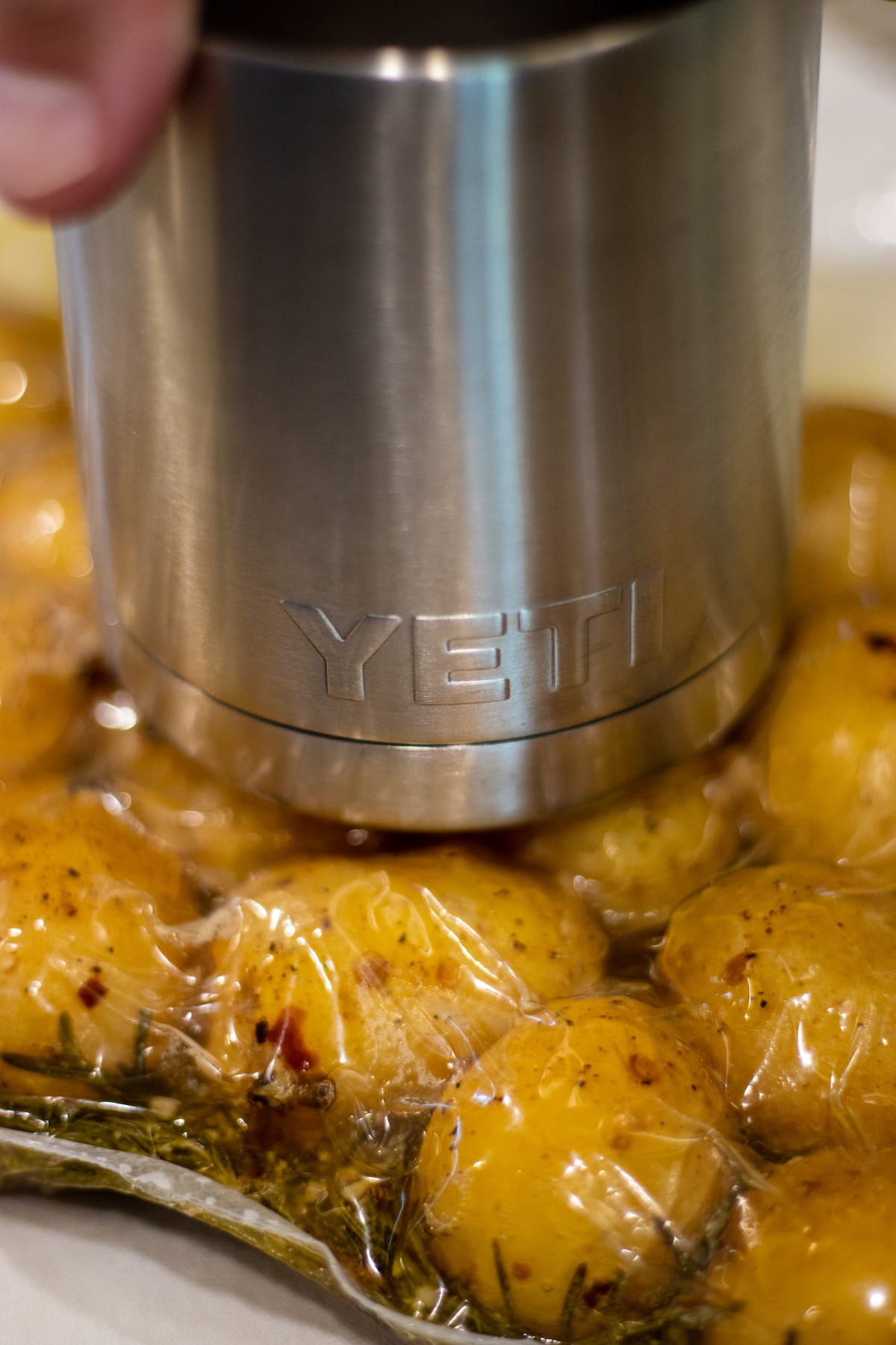 Yukon gold potatoes in a bag being smashed by a yeti tumbler.