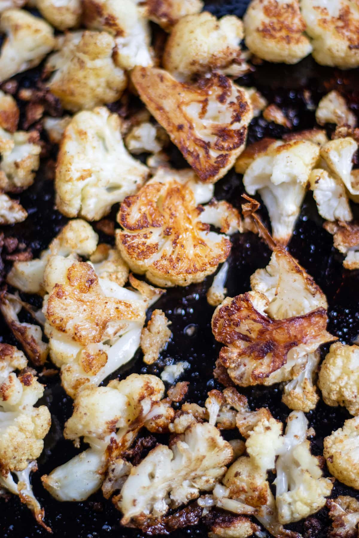 Roasted cauliflower on a baking pan.